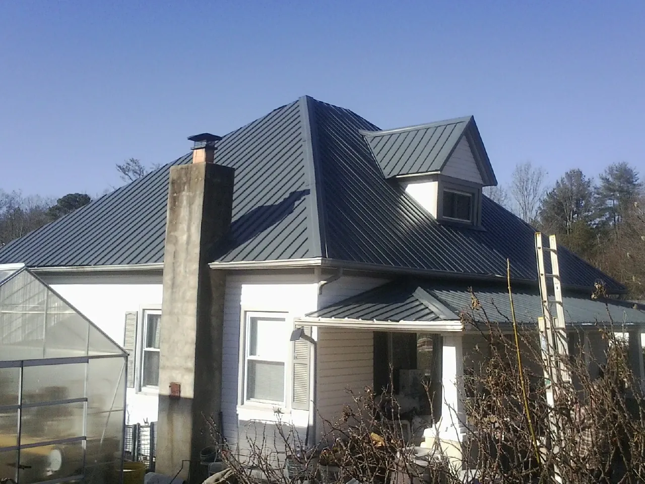 Dark blue standing seam metal roof on a white farmhouse with dormer — Slate & Tile Roof Repair by Roofing Brothers in Poughquag