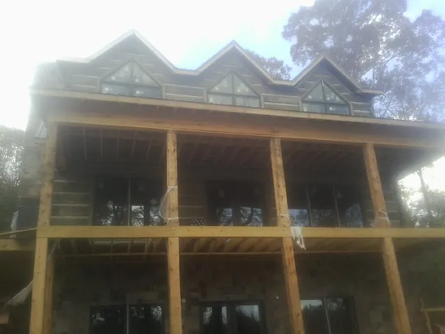 Dormers and porch framing on a large log home under construction — Roof Coating work by our crew in Poughquag