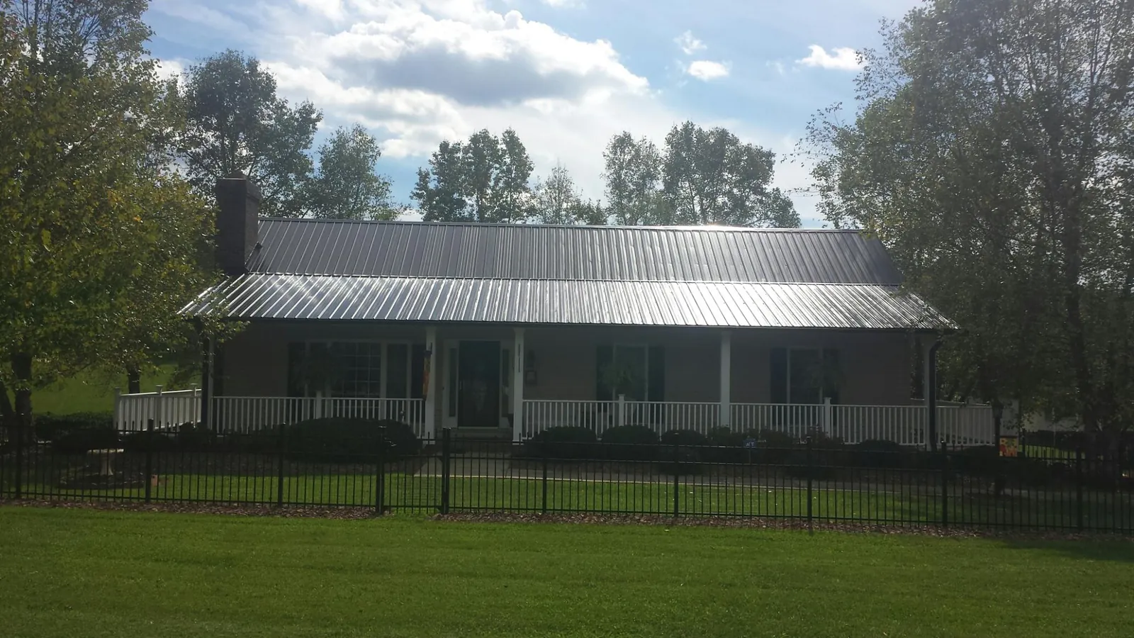 Gray metal roof on a brick ranch with a full width front porch — Gutter Guard Installation work by our crew in Poughquag