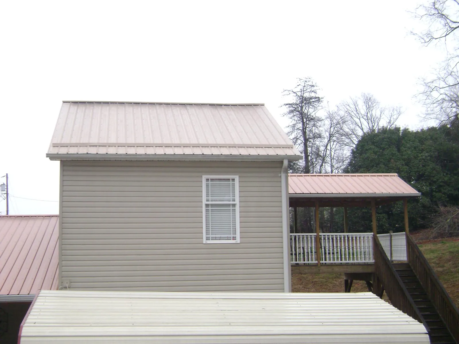Tan metal roofs on a two story addition and attached porch, from a Roof Replacement job in Poughquag
