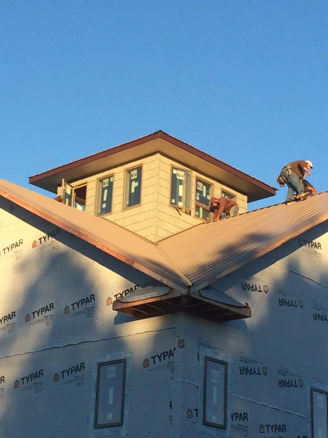 Roofers working around a rooftop cupola on a new metal roof at sunset — Roof Waterproofing in Poughquag by Roofing Brothers